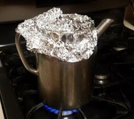 kettle covered in aluminum foil on stovetop